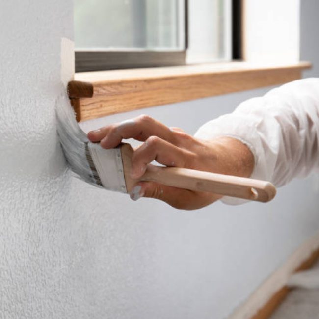 Man painting interior of home in gray paint